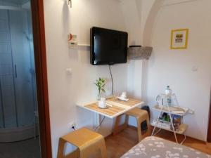 um pequeno quarto com uma mesa e uma televisão na parede em City center blue sky house em Postojna