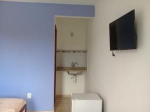 um quarto com uma televisão e um lavatório num quarto em Suites PRISCO BEACH em Cabo Frio