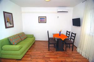 ein Wohnzimmer mit einem grünen Sofa und einem Tisch in der Unterkunft Apartman Luca in Zečevo