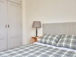 a bedroom with a bed with a plaid blanket and a lamp at Apartamento Tíbula Teatro Parking in Mérida