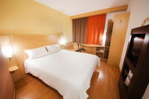 a hotel room with a bed, chair, and nightstand at Ibis Yaroslavl Center in Yaroslavl