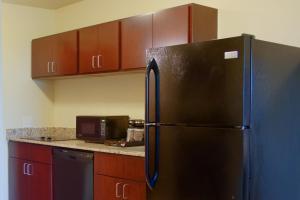 a black refrigerator in a kitchen with wooden cabinets at Cobblestone Inn & Suites-Winterset in Winterset