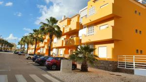 um edifício amarelo com carros estacionados num parque de estacionamento em Sunshine Apartment em Tavira