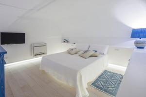 ein weißes Schlafzimmer mit einem Bett und einem TV in der Unterkunft Sapore di Sale in Atrani