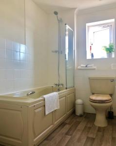 een badkamer met een bad, een toilet en een wastafel bij Waterside in Rye
