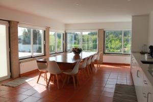 a kitchen with a table and chairs and windows at Casa da Rosa in Paredes de Coura