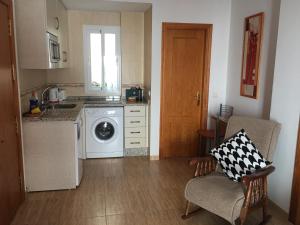 a kitchen with a washing machine and a chair at Apartamento Steven in Ardales