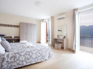 a white bedroom with a bed and a large window at SALA COMACINA RESIDENCE NO 4 in Sala Comacina