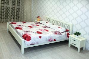 ein Schlafzimmer mit einem weißen Bett mit roten Blumen darauf in der Unterkunft Standard Plus Apartment in Poltawa