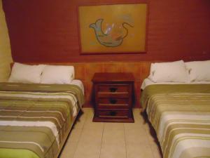 two beds in a room with a table between them at Hotel El Rancho in Navojoa