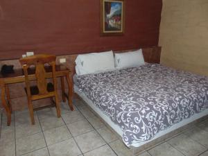 a bedroom with a bed and a table and a chair at Hotel El Rancho in Navojoa