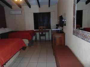 Habitación con 2 camas, mesa y espejo. en Hotel El Rancho en Navojoa