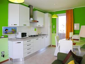a kitchen with green walls and white cabinets and a microwave at Bosco dell'Impero Nettuno in Bibione