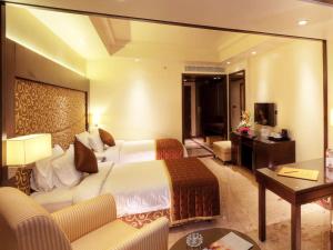 a hotel room with a large bed and a living room at Anandha Inn Convention Centre and Suites in Pondicherry