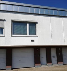 un edificio blanco con cuatro puertas de garaje. en Apartment-Ferienwohnung in Mainaschaff, en Mainaschaff