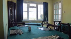 a dining room with a green table and windows at Chancery House in Highbray
