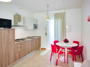a kitchen with a table and red chairs and a table at Bosco dell'Impero Nettuno in Bibione