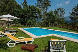 a group of chairs and an umbrella next to a swimming pool at Quinta da Baldieira in Mondim de Basto