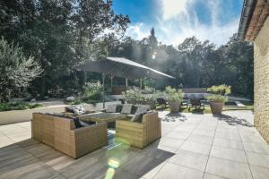 a patio with two couches and an umbrella at La Villa Dupont d'Avignon in Villeneuve-lès-Avignon