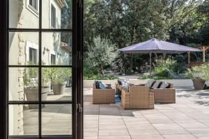 a patio with couches and an umbrella and an umbrella at La Villa Dupont d'Avignon in Villeneuve-lès-Avignon