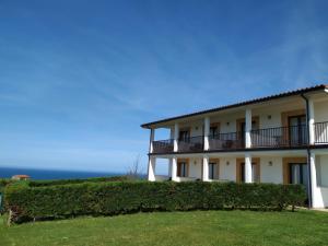 un gran edificio blanco con arbustos delante en El Ribero de Langre en Langre