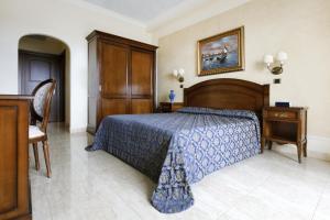 a hotel room with a bed, desk, and chair at Grand Hotel President in Olbia