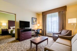 Cobblestone Hotel & Suites - McCook في ماكوك: غرفه فندقيه فيها اريكه وسرير وتلفزيون