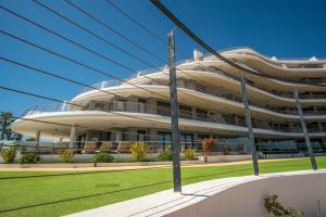 a large white building with a green lawn in front at Infinity View Paradise Apartment in Arenales del Sol