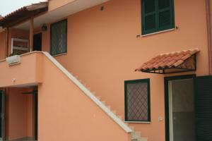 pomarańczowy dom ze schodami i zielonymi okiennicami w obiekcie I Villini B&B w mieście Fiumicino