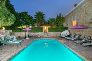 a swimming pool with chairs and umbrellas in a yard at Betty's Boutique Hotel in Mossel Bay