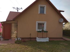 een geel huis met een raam en een bad in de tuin bij Dom wakacyjny u Alicji in Pasym