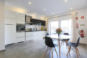 バレアルにあるVitamin Sea, The Terrace Apartmentの白いキャビネット、テーブルと椅子付きのキッチンが備わります。