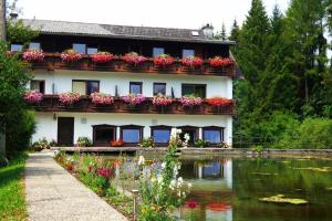a house with flowers in front of a lake at Wieselmühle Forellenhof in Grünau im Almtal