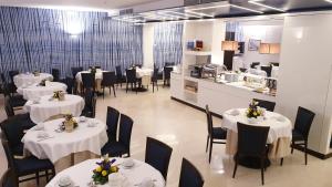a restaurant with white tables and chairs and a kitchen at Hotel La Meridiana in Sorrento