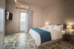a bedroom with a bed and a large window at MELIES- Seaside Boutique Apartments in Chorto