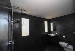 a black bathroom with a toilet and a sink at Hôtel confidentiel Le Grecale in Pianottoli-Caldarello