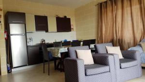 a kitchen with chairs and a table and a refrigerator at Palm Court Apartment in Xlendi