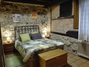 um quarto com uma cama num quarto com paredes de pedra em Hotel La Casa Chacinera em Candelario