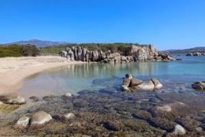 a beach with rocks in the water at Hôtel confidentiel Le Grecale in Pianottoli-Caldarello