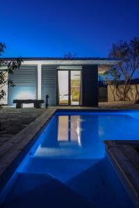 a swimming pool in front of a house at night at Hôtel confidentiel Le Grecale in Pianottoli-Caldarello