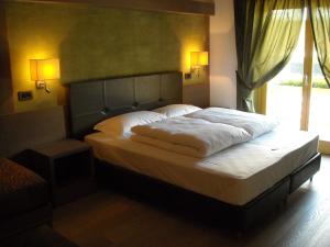 a bedroom with a bed with white sheets and a window at Dolomiti Lodge Villa Gaia in Venas +29 photos