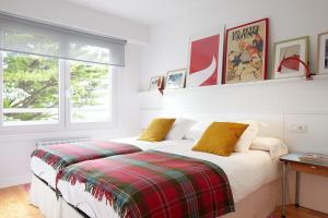 a bedroom with a bed with a plaid blanket at ATeRIAN PILARTXO ENEA in Zarautz