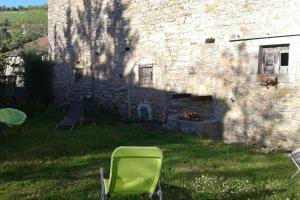 una sedia verde seduta di fronte a un edificio in pietra di Gite Gabrielle a Saint-Jean-dʼAlcapiès