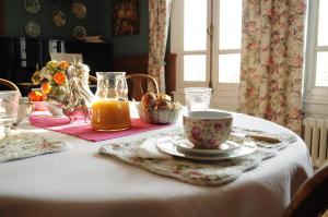 una mesa con una taza de zumo de naranja y un plato de pan en La Liniere, en Honfleur