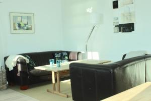 a living room with a black leather couch and a table at Grastenhus Guesthouse in Thurø By