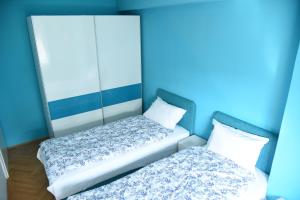 two beds in a room with blue walls at Kiara Apartments Skopje in Skopje