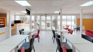 a dining room with tables and chairs and windows at Kyriad Direct Achères in Achères