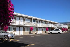 a hotel with two cars parked in a parking lot at Plaza Motel in Penticton