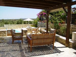 un patio con 2 sillas, una mesa y una piscina en Villa Emilie, en Agios Dimitrios