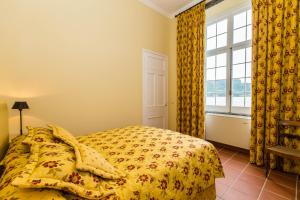 a bedroom with a bed with a yellow comforter and a window at Casa Dos Barcos Furnas in Furnas